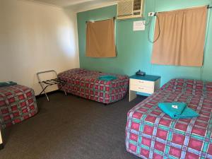 a room with two beds and a chair in it at Coyote Inn in Cloncurry