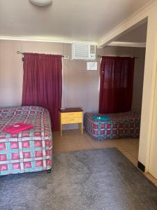 a bedroom with a bed and a table and curtains at Coyote Inn in Cloncurry +3 photos