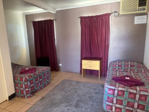 a room with two beds and red curtains at Coyote Inn in Cloncurry