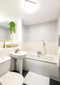 a bathroom with a white tub and a sink and a toilet at LushMint&Sound in Bristol