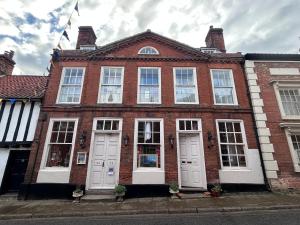 a red brick building with white doors and windows at Walsingham Bakehouse in Little Walsingham
