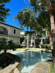 a swimming pool in front of a house with palm trees at Pousada Corsario Buzios in Búzios