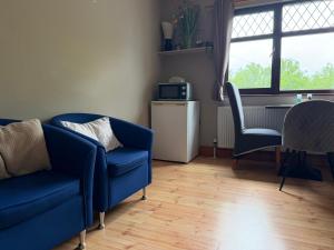 a living room with a blue couch and two chairs at Davmar House Blarney in Cork