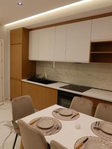 a kitchen with a table with chairs and white cabinets at Marbel Sea View in Shëngjin