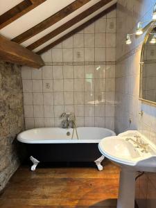 a bathroom with a bath tub and a sink at Maison Camille in Hotton