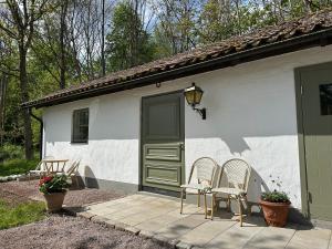 a white house with two chairs and a green door at Orangeriet Björkelund in Skövde