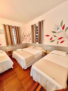 a room with three beds in a room at Pousada Flores do Farol in Salvador