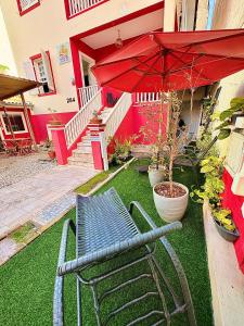 a red umbrella and a bench in front of a house at Pousada Flores do Farol in Salvador