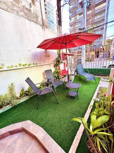 a patio with chairs and a red umbrella at Pousada Flores do Farol in Salvador
