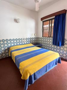 a bedroom with a bed with a yellow and blue blanket at Hotel California in Mazatlán