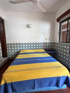 a bedroom with a bed with a yellow and blue blanket at Hotel California in Mazatlán