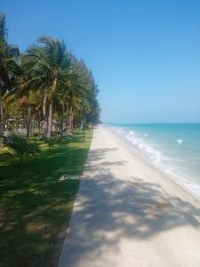 an empty beach with palm trees and the ocean at Splash Paradise Villa in Cha Am