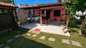 a backyard with a pink house with a table and chairs at Casa da Dinda à 650m da praia de Itaúna in Saquarema