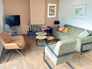 a living room with a couch and chairs and a tv at Pet-Friendly Coastal Getaway in Breskens
