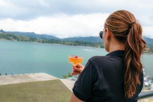 a woman holding a drink overlooking a lake at Bliss Sanctuary Vista - Glamping and Club in Guatapé