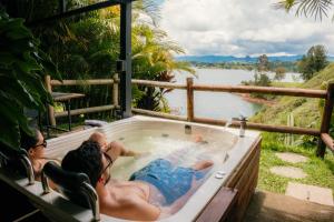 two people sitting in a jacuzzi tub overlooking a river at Bliss Sanctuary Vista - Glamping and Club in Guatapé +97 photos