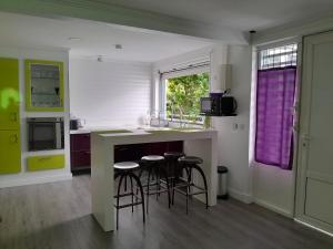 a kitchen with a counter with stools and a sink at CAP COULEURS Guadeloupe in Lamentin
