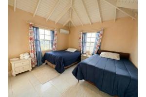 a bedroom with two beds and two windows at Pink Sands-At Bel Air in Saint Philip +13 photos