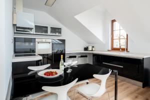 a kitchen with a dining table and white chairs at Kopernik Loft Jelenia Góra in Jelenia Góra