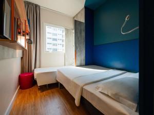 two beds in a room with a blue wall at ibis budget Santos Gonzaga in Santos +177 photos