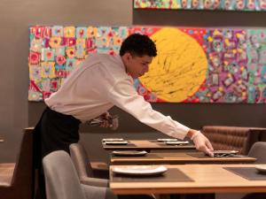 a man standing at a table preparing food at Novotel Curitiba Batel in Curitiba