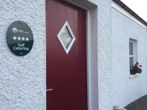 eine rote Tür an der Seite eines weißen Gebäudes in der Unterkunft Brookvale Cottage in Downpatrick + 2 Fotos
