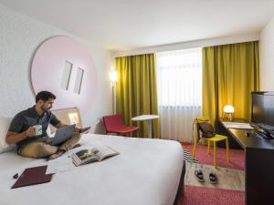 a man sitting on a bed in a hotel room at ibis Styles Lyon Bron Eurexpo in Bron