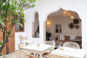 a restaurant with white tables and chairs and a patio at Riad Lamzia in Marrakesh