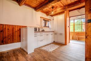 a kitchen with white cabinets and a wooden ceiling at Roubenka Kubovka in Černá v Pošumaví