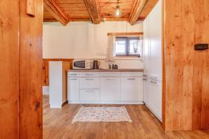 a kitchen with white cabinets and a wooden ceiling at Roubenka Kubovka in Černá v Pošumaví +7 photos