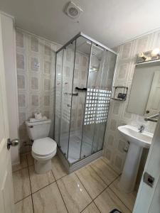 a bathroom with a shower and a toilet and a sink at Hotel y Restaurant Mackenna in Osorno +38 photos