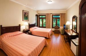 a hotel room with two beds and a desk at Hotel Aranjuez Cochabamba in Cochabamba