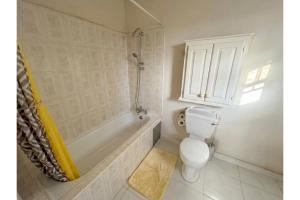 a bathroom with a toilet and a tub and a shower at Pink Sands-At Bel Air in Saint Philip