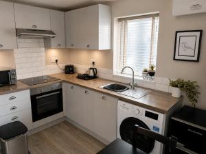 a kitchen with white cabinets and a dishwasher at Central Apartments Cannock in Cannock +28 photos