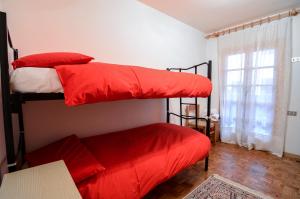 sypialnia z 2 łóżkami piętrowymi i czerwoną pościelą w obiekcie Appartamenti Il Sogno w mieście Campodolcino