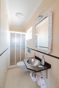 a bathroom with a sink and a toilet and a mirror at Atico Solpor Patos in Nigrán