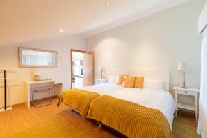 a bedroom with a large white bed with yellow sheets at Atico Solpor Patos in Nigrán