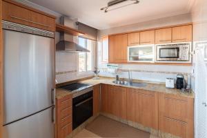 a kitchen with wooden cabinets and a stainless steel refrigerator at Atico Solpor Patos in Nigrán