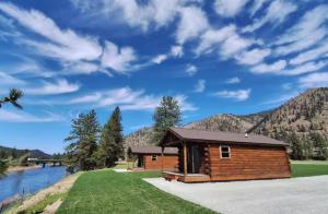 a cabin with a view of a river and mountains at Micham's Clark Fork River Retreat - River Front, Mountain View, Fire Pit - Cabin 1 in Superior