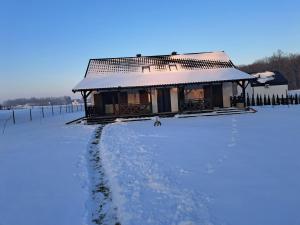 a house with a snow covered roof on a snow covered field at Leśna przystań in Trupel
