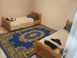 two beds in a room with a rug on the floor at Maison ras angela in Bizerte +6 photos