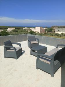 a group of patio chairs sitting on top of the sand at Maison ras angela in Bizerte