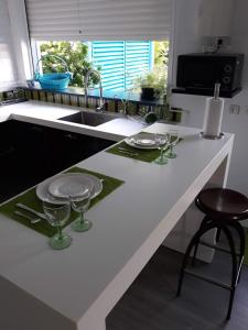 a kitchen with a white counter with wine glasses on it at CAP COULEURS Guadeloupe in Lamentin
