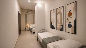 a small room with two beds and paintings on the wall at The Arco Rooms in Pomigliano dʼArco