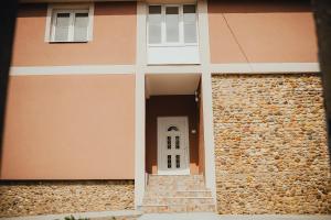 a house with a white door and a stone wall at LUX apartman savić in Aleksinac