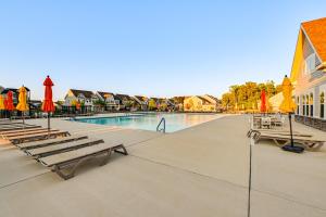 a pool with benches and umbrellas next to a building at Beach Shuttle! Spacious Bishop’s Landing Retreat in Ocean View