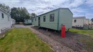 a green trailer with a red fire hydrant in a yard at Shore&Meadow Holiday Lets - Luxury 8 berth caravan at Regent Bay in Morecambe