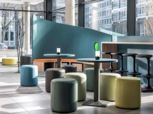 a lobby with tables and stools in a building at ibis Styles Stuttgart Vaihingen in Stuttgart