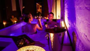 a man and woman in a bathtub with purple lights at iRelax studio - privatni wellness in Prague