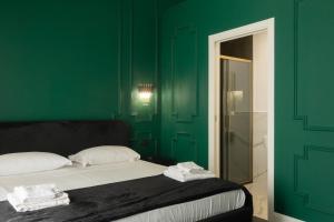 a bedroom with green walls and a bed with white pillows at Four Rooms Luxury Suite in Palermo